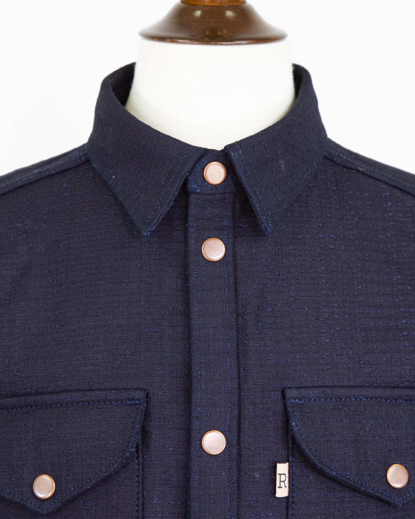 Navy blue shirt with button details on a mannequin against a white background
