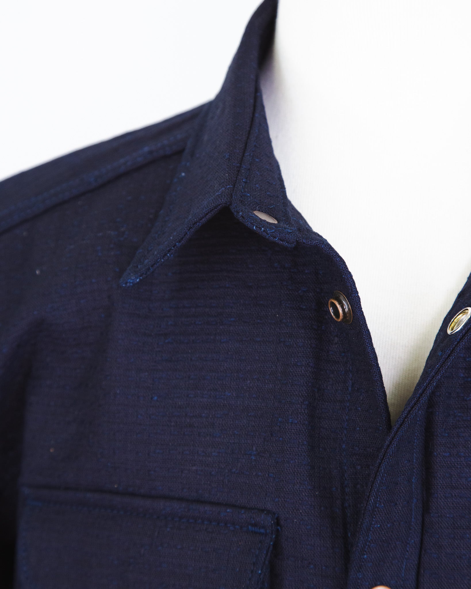 Close-up of a navy blue shirt with a collar and buttons on a white background