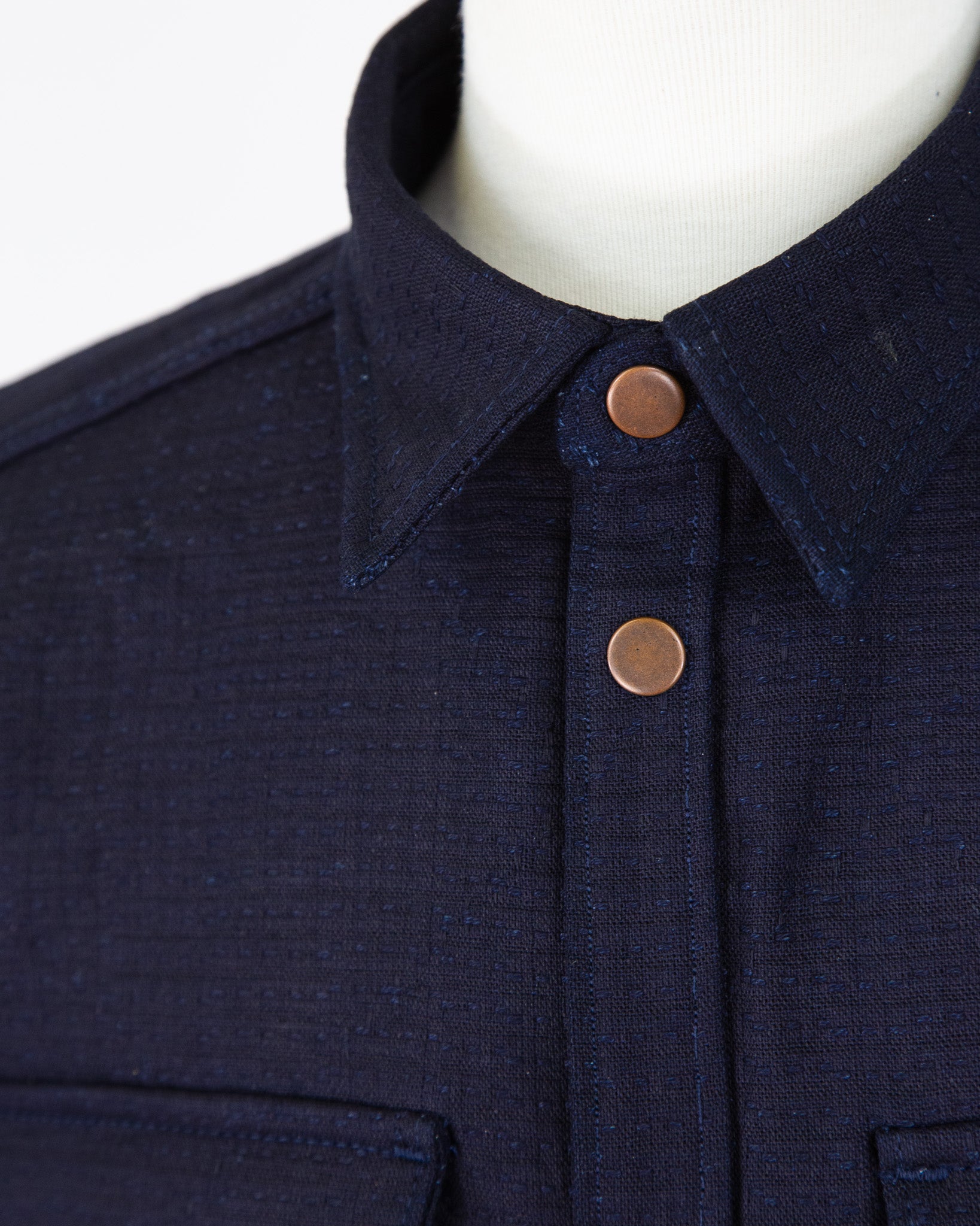 Navy blue jacket with copper buttons on a mannequin against a white background