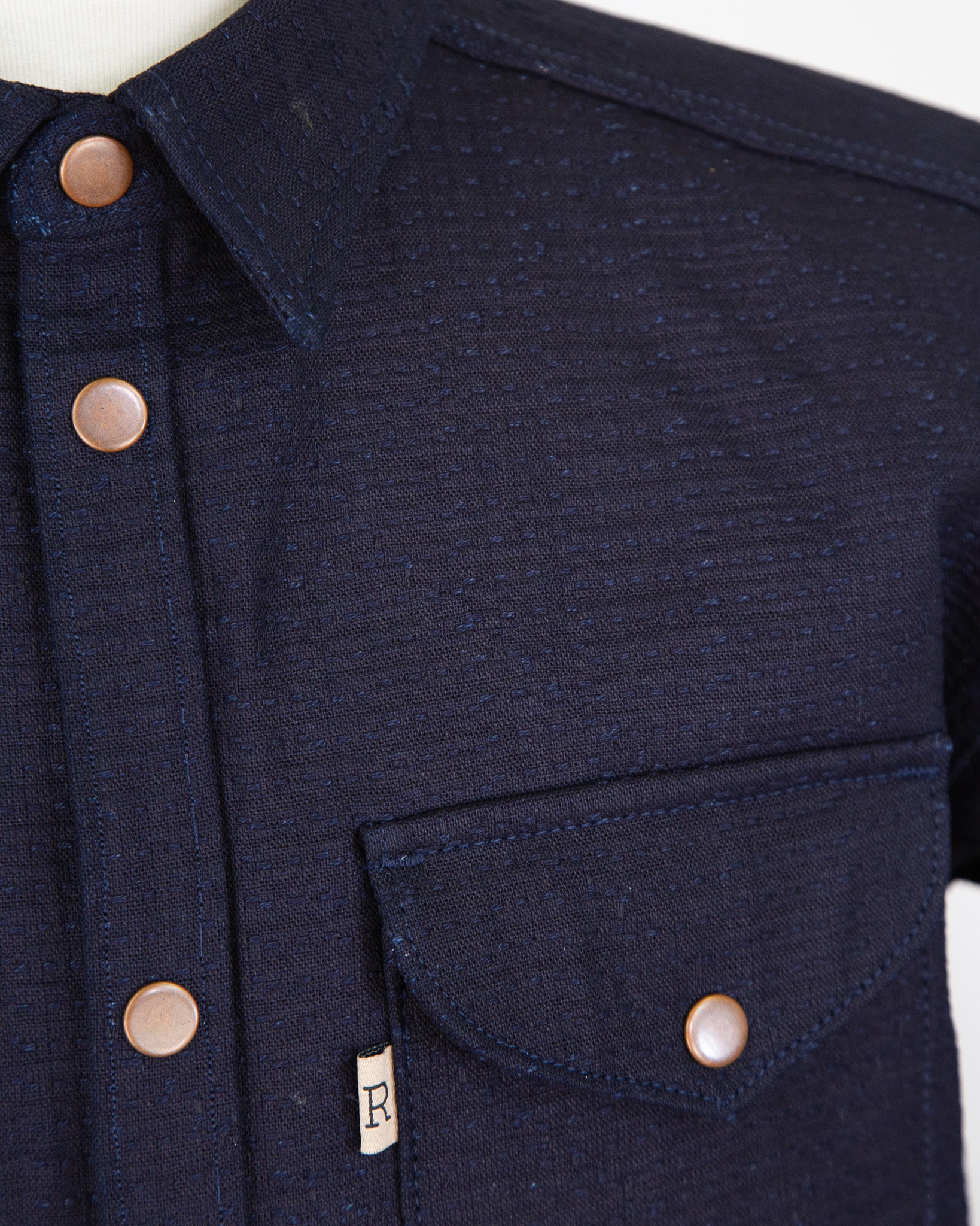 Navy blue denim jacket with button details on a white background