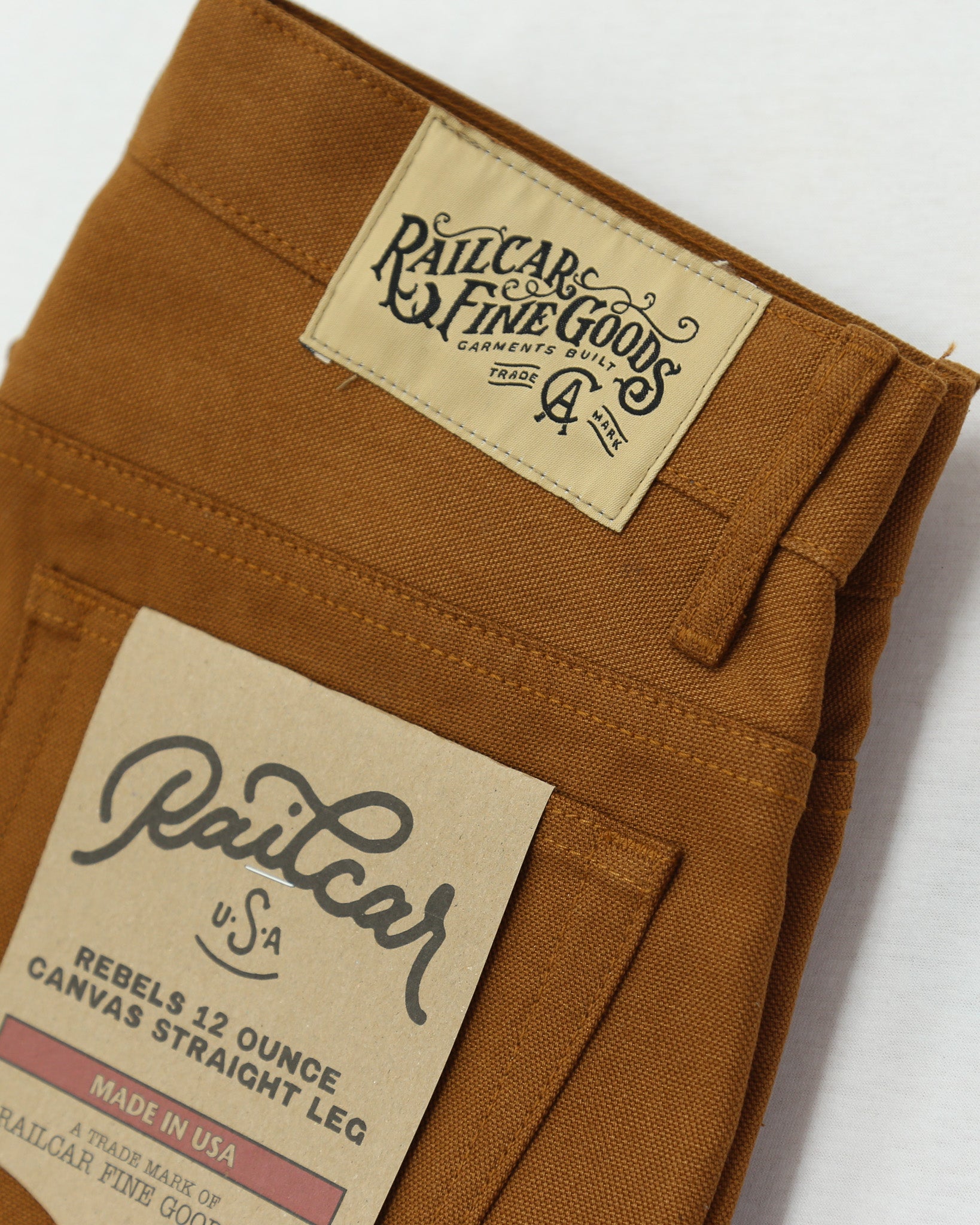 Brown canvas pants with 'Railcar Fine Goods' label on a white background