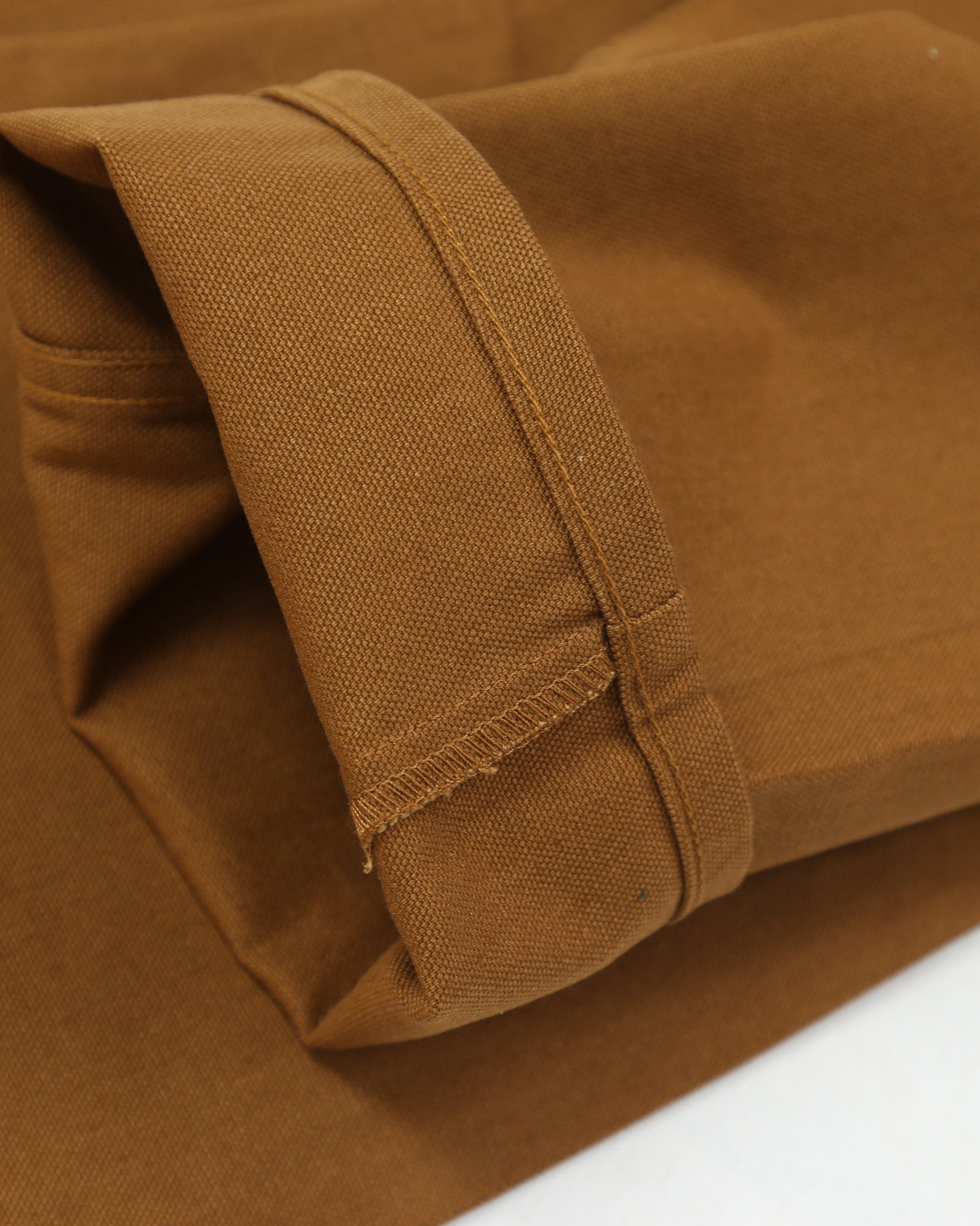 Close-up of brown canvas fabric with a visible seam on a white background