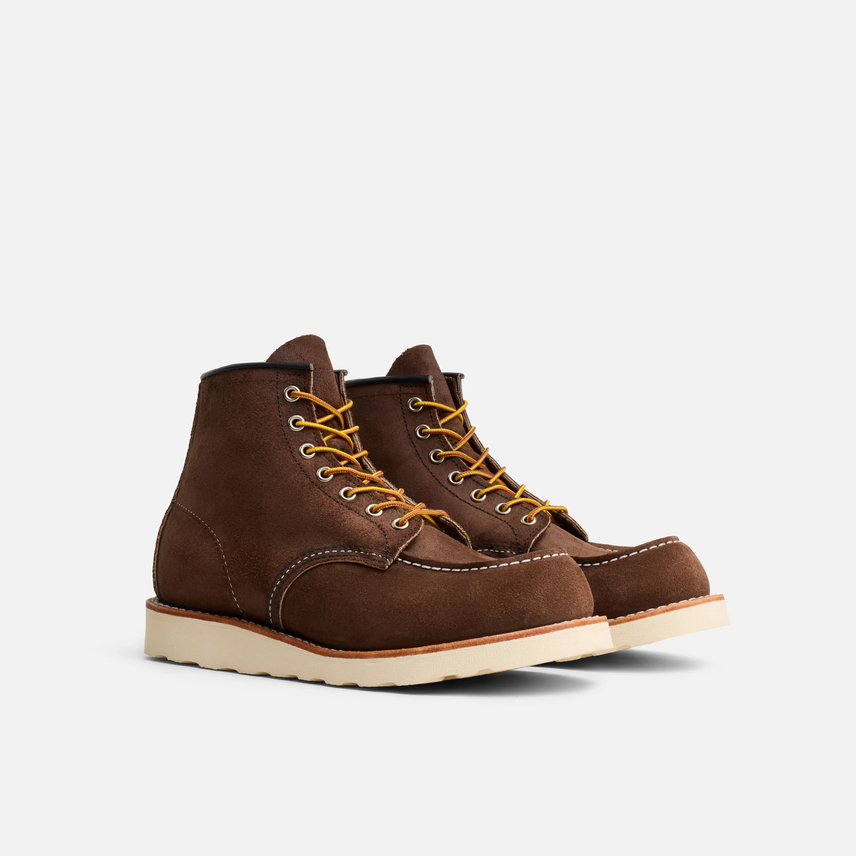 Pair of brown leather boots with yellow laces on a white background