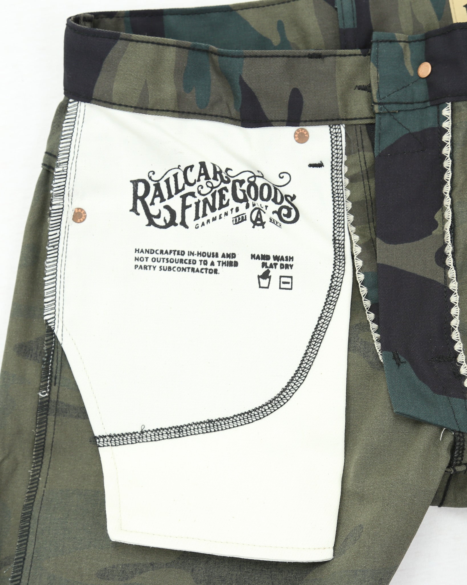 Camouflage pants with a white label displaying text and branding.