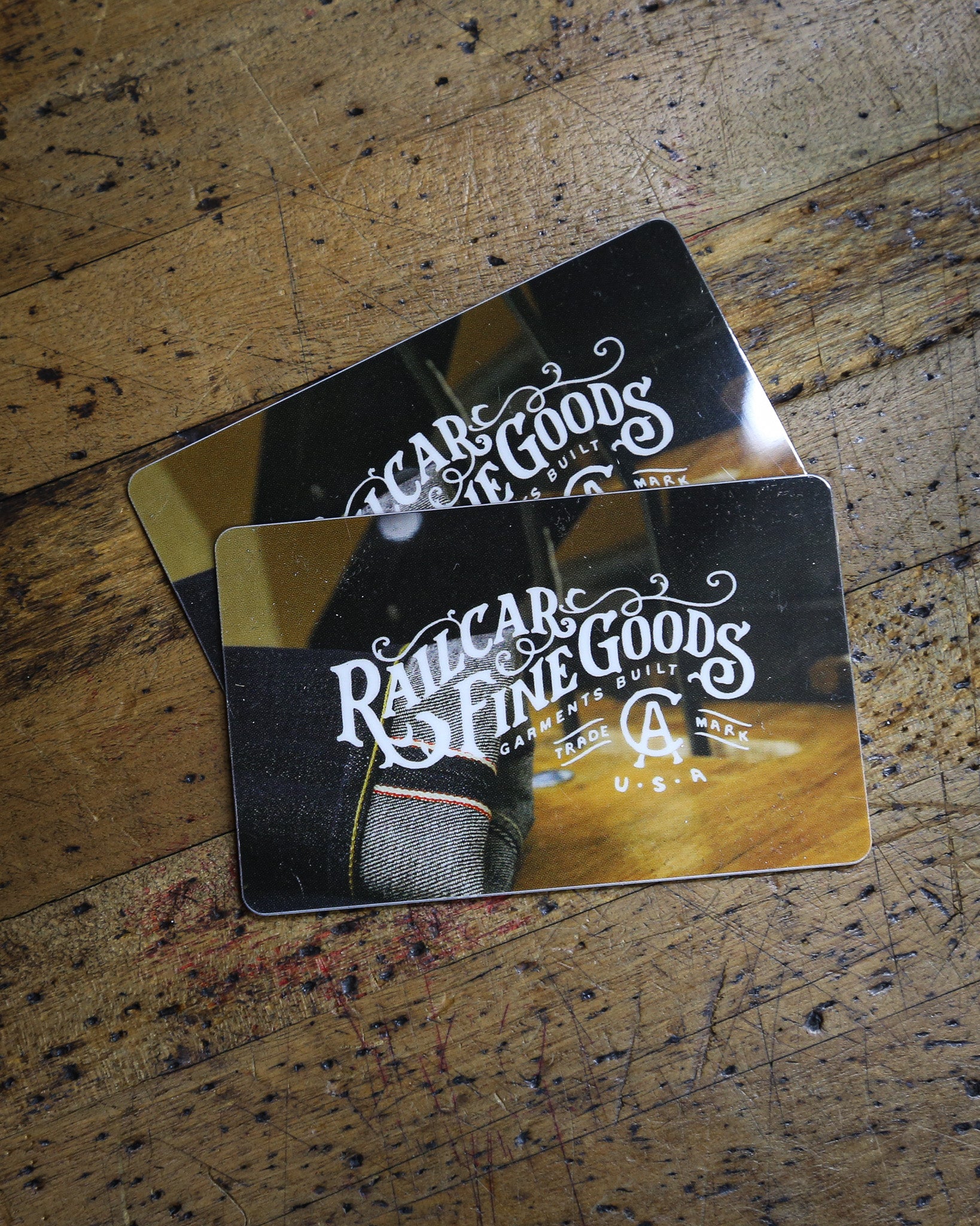 Two 'Railcar Fine Goods' branded gift cards on a wooden surface