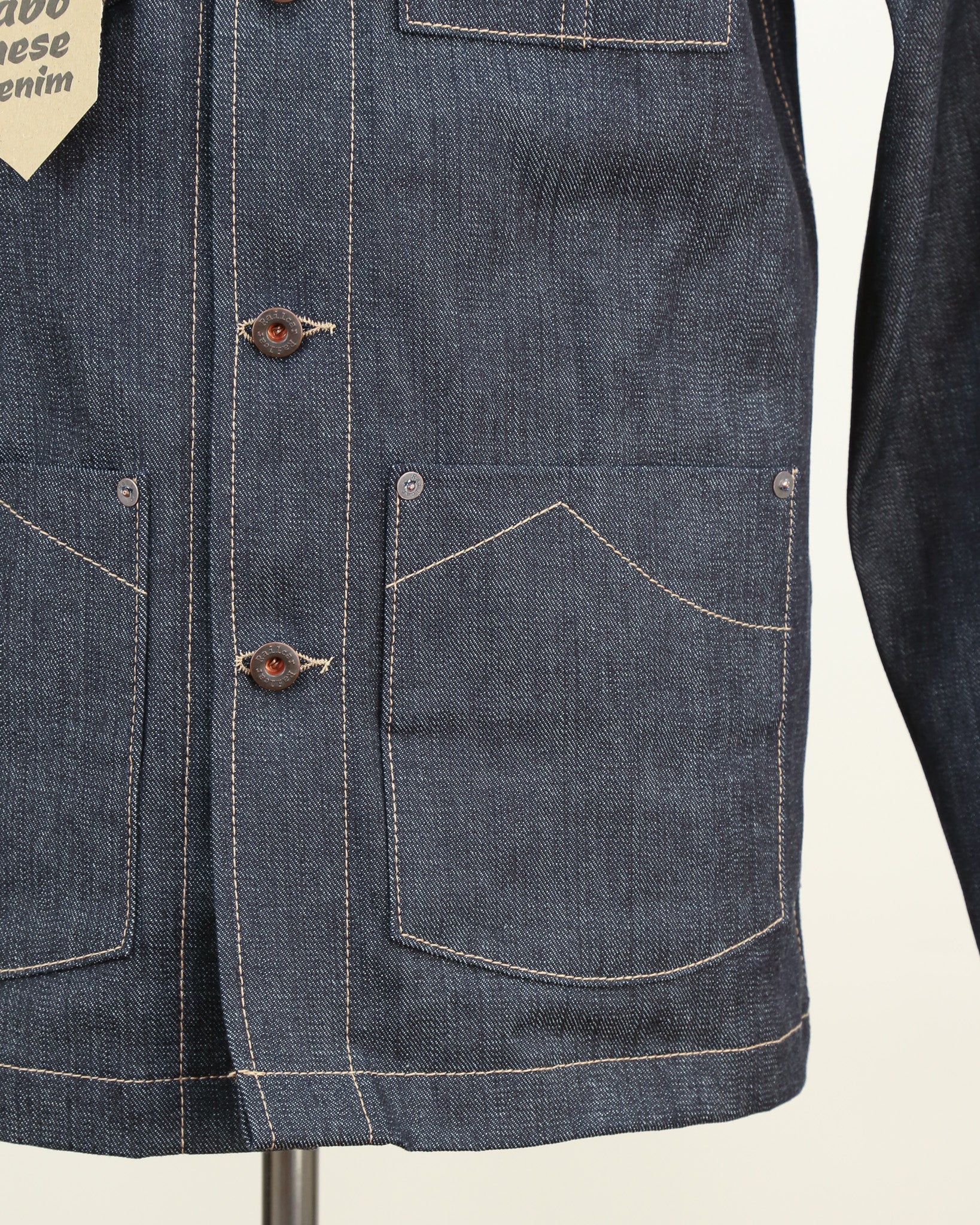 Close-up of a blue denim jacket with visible stitching details on a white background