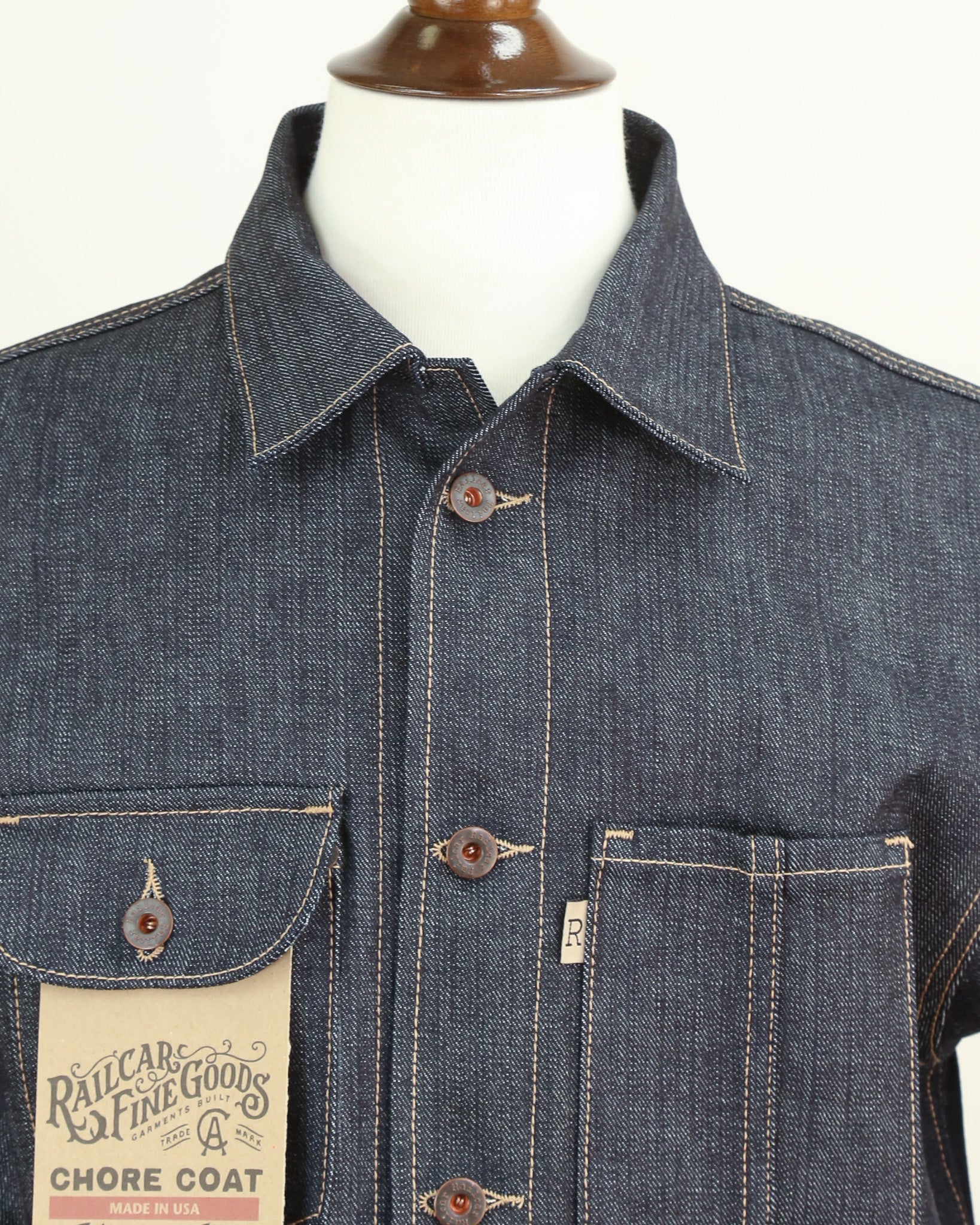 Blue denim chore coat on a mannequin with a visible brand label.