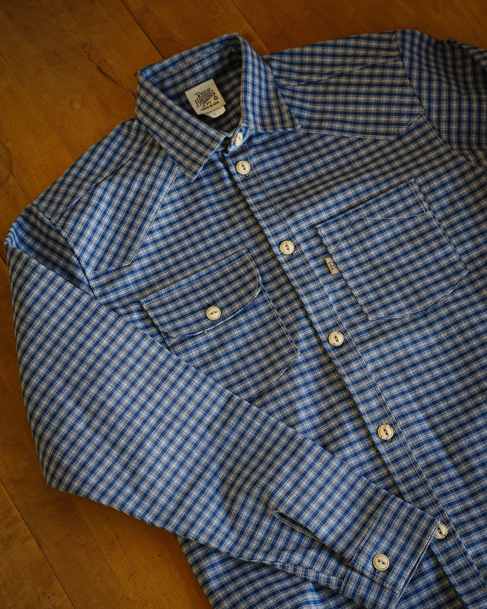 Folded blue and white checkered shirt on a wooden surface