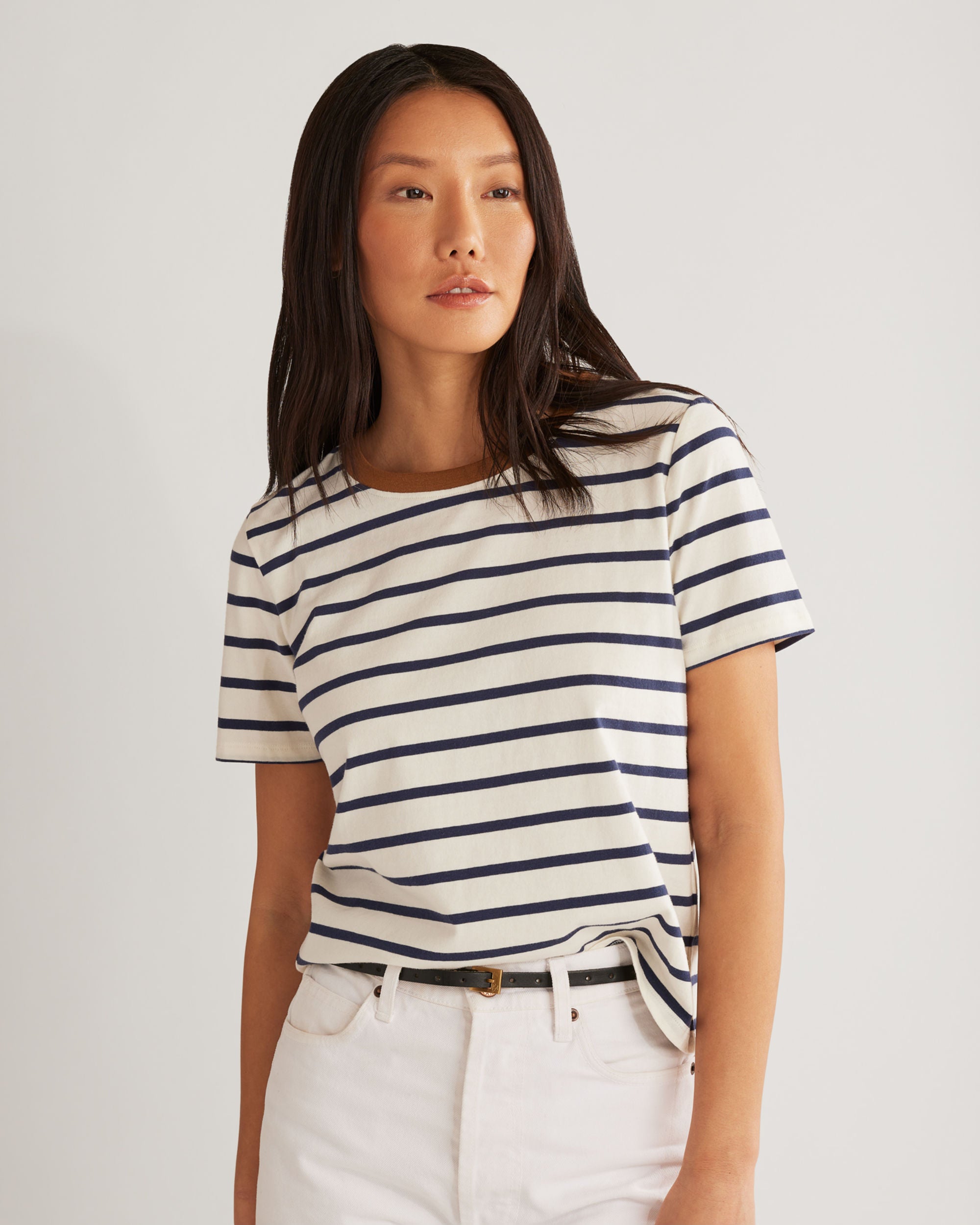 Woman wearing a striped shirt and white pants on a plain background