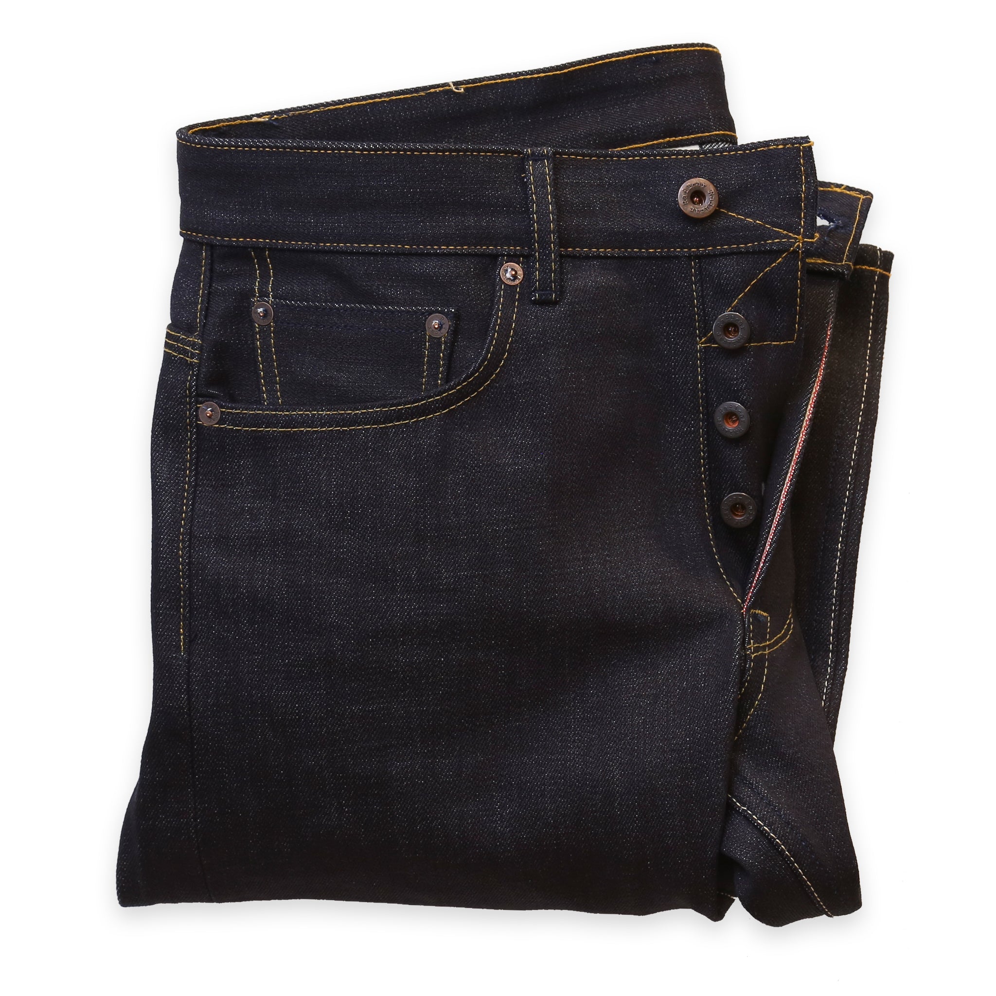 A pair of folded  dark denim jeans showing the button replacement service performed on them.